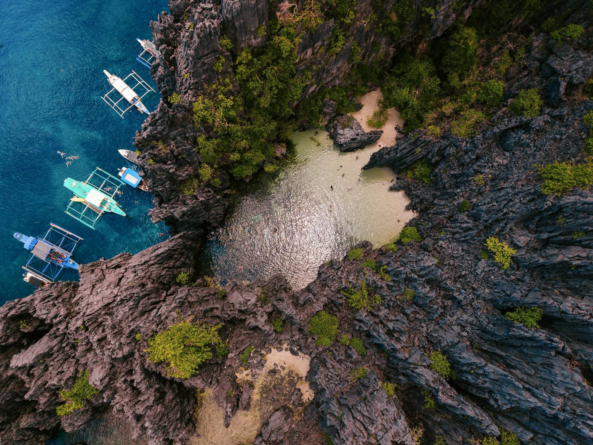 Bangka boats moored below the karst cliffs of El Nido, seen from a drone